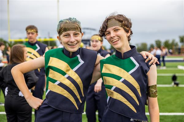 Two IHS band members smile on the football field